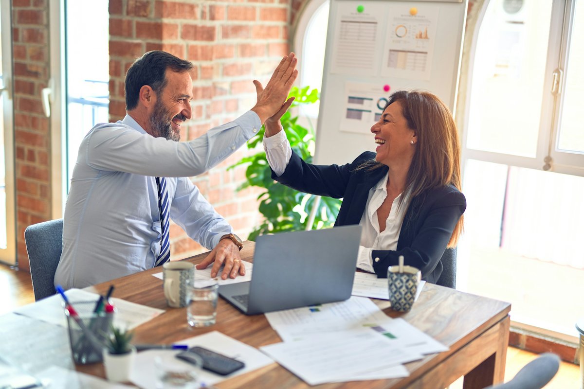 Advisor and business owner high-fiving across a desk