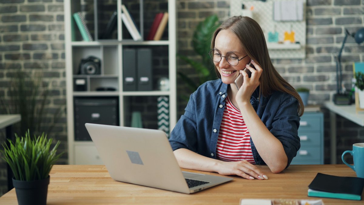 Woman on a phone call while working on a laptop